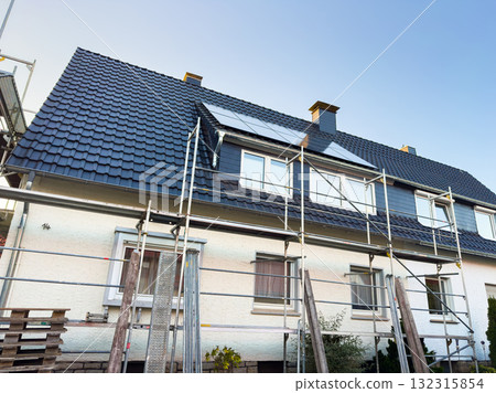 Roofing renovations taking place on a suburban home under clear blue skies Roofing renovations taking place on a suburban home under clear blue skies 132315854