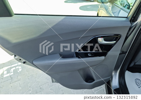 Sleek interior of a modern car showing the door panel and controls on a bright day at a dealership 132315892