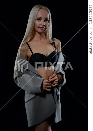 Elegant model poses confidently in stylish grey blazer with black lingerie 132315925