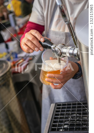 Close-up of person pouring draft beer from a tap into a plastic cup at an outdoor event or bar. Concept of beer, refreshment, social leisure, casual drinking, celebration holiday fair Close-up of person pouring draft beer from a tap into a plastic cup at an outdoor event or bar. Concept of beer, refreshment, social leisure, casual drinking, celebration holiday fair 132315965