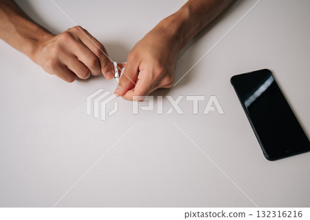 Close-up top view of man preparing to cleaning smartphone screen, opening wet wipe and alcohol pad, ensuring hygiene and removing dirt and fingerprints from device surface sitting at desk at home. 132316216