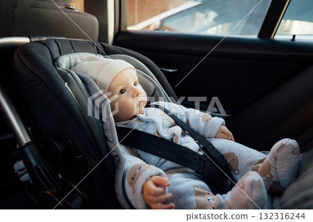 Baby sitting in an infant car seat, safety travelling by car with little child. Little baby fastened with seat belt in safety car seat. Road trip lifestyle child care transportation rear-facing. Baby sitting in an infant car seat, safety travelling by car with little child. Little baby fastened with seat belt in safety car seat. Road trip lifestyle child care transportation rear-facing. 132316244