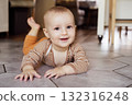 Happy, laughing baby lying on tiled floor at home for child development, wellness and growth. Cheerful active little infant kid training physical skills, smiling, learning to crawl, playing and relax. 132316248