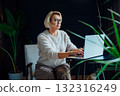 Smiling 50's stylish, confident mature businesswoman, middle aged experienced senior female professional, business coach, mentor, therapist, counselor working on laptop in office. Female leader 132316249