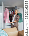 Middle aged woman selecting clothes from wardrobe for donating to Charity shop. Decluttering, Sorting clothes and Cleaning Up. Reuse, second-hand concept. Conscious consumer, sustainable lifestyle. 132316255