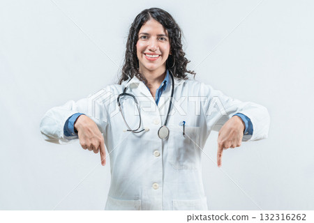 Smiling female doctor pointing down at a space isolated. Young female doctor showing an advertisement down Smiling female doctor pointing down at a space isolated. Young female doctor showing an advertisement down 132316262