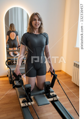 Female adjusting reformer exercises, Woman performing Pilates exercises on reformer machine in gym Female adjusting reformer exercises, Woman performing Pilates exercises on reformer machine in gym 132316457