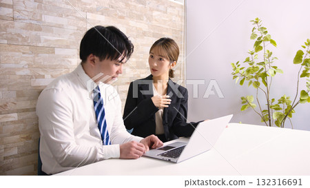 Young men and women having a meeting while looking at a computer in an office 132316691