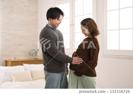A young couple standing by the window, a pregnant woman A young couple standing by the window, a pregnant woman 132316720