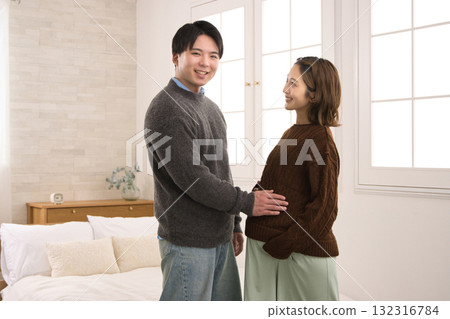 A young couple standing by the window, a pregnant woman A young couple standing by the window, a pregnant woman 132316784