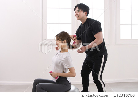 Young woman receiving training from a personal trainer Young woman receiving training from a personal trainer 132316796