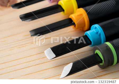 Close-up of a wooden board and the cutting edge of a chisel 132319487