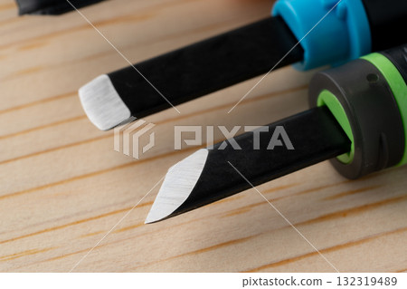 Close-up of a wooden board and the cutting edge of a chisel 132319489