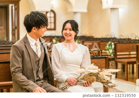 Wedding hall, bride and groom sitting on a bench in the chapel (Virgin aisle, church, chapel) Wedding hall, bride and groom sitting on a bench in the chapel (Virgin aisle, church, chapel) 132319550