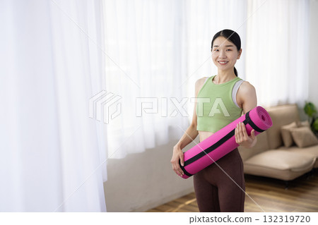 Smiling middle-aged woman holding a yoga mat 132319720