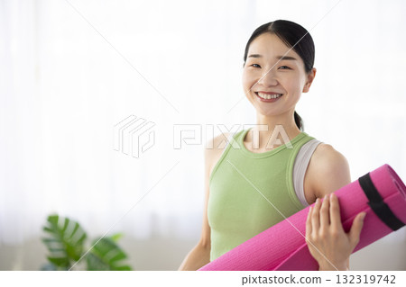 Smiling middle-aged woman holding a yoga mat 132319742