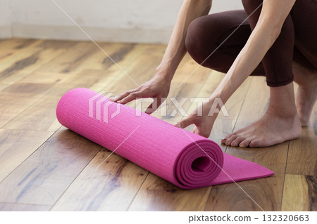 Close-up of a woman's hands preparing a yoga mat Close-up of a woman's hands preparing a yoga mat 132320663