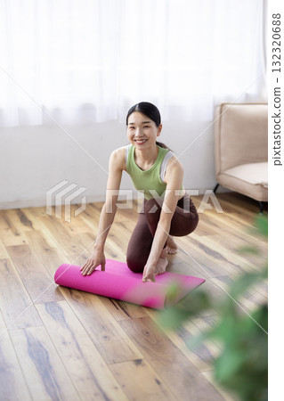 Middle-aged woman preparing a yoga mat 132320688