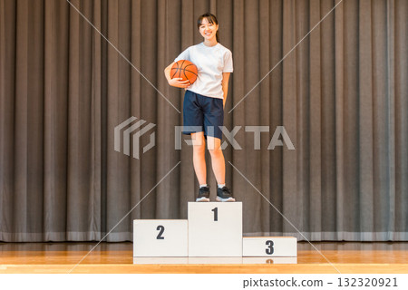 Elementary school, junior high school, and high school girls in gym clothes standing on the podium on the stage of a gymnasium 132320921