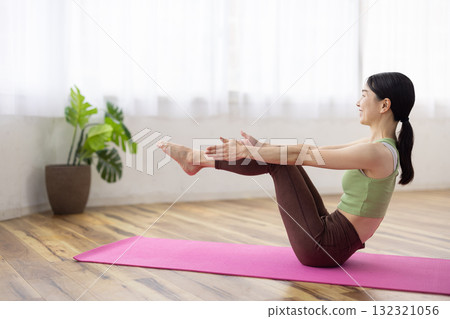 Middle-aged woman doing yoga poses on a yoga mat 132321056