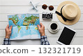 Traveler planning vacation looking at world map with travel accessories 132321719