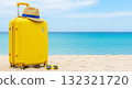 Yellow suitcase with straw hat and sunglasses resting on sandy beach 132321720