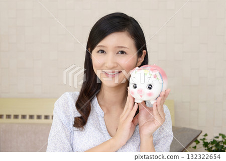 有豬錢箱的微笑的婦女 132322654