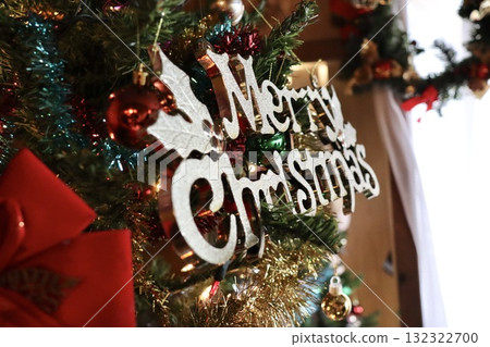 Close-up of a Christmas tree with a shining "Merry Christmas" ornament. Winter advertising material. 132322700