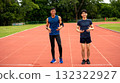 Two Asian men in athletic wear smiling and standing on an outdoor running track, ready for fitness or workout session. Concept of friendship, active lifestyle, and healthy living 132322927