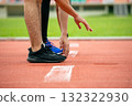 Close-up of two athletes in ready position on a starting line at an outdoor running track. Concept of competition, speed, motivation, determination, and preparation for sports or fitness goals 132322930