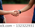 Close-up of two male athletes shaking hands on an outdoor running track, symbolizing sportsmanship, teamwork, respect, and cooperation after competition or fitness training session 132322931