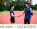 Two Asian male athletes shaking hands on an outdoor running track, symbolizing teamwork, sportsmanship, and respect after workout or competition. Concept of fitness partnership and motivation 132322932