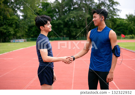 Two Asian male athletes shaking hands on an outdoor running track, symbolizing teamwork, sportsmanship, and respect after workout or competition. Concept of fitness partnership and motivation Two Asian male athletes shaking hands on an outdoor running track, symbolizing teamwork, sportsmanship, and respect after workout or competition. Concept of fitness partnership and motivation 132322932