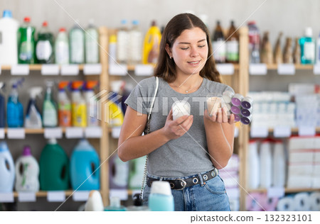 Young woman choosing scented candles in household goods store 132323101