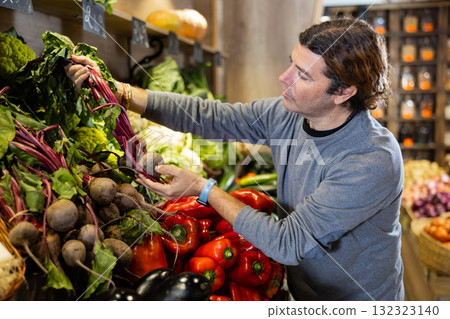 Adult man buyer chooses beets in shop 132323140