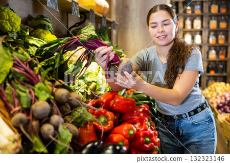 Woman diligently picking out beets to buy in vegetable aisle of supermarket Woman diligently picking out beets to buy in vegetable aisle of supermarket 132323146