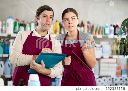 Two sellers, man and woman, makes notes on an paper - conducts an inventory in supermarket 132323156