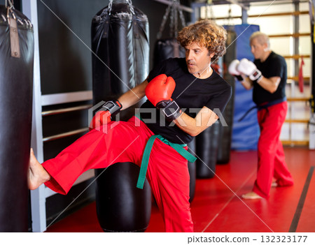 Strong man practicing punches on punching bag. Boxing training Strong man practicing punches on punching bag. Boxing training 132323177