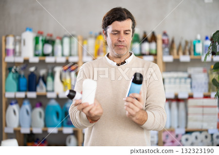 Man chooses deodorant aerosol can or air freshener in supermarket 132323190