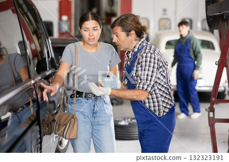 Male mechanic consulting female client on car door 132323191