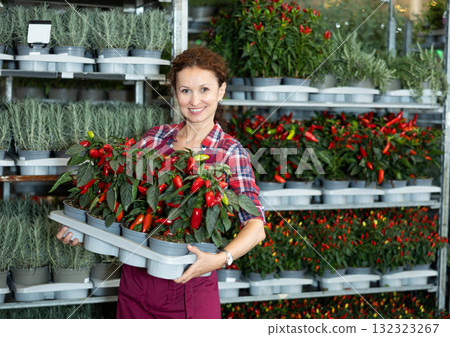 Middle-aged saleswoman holding garden-pots with decorative pepper 132323267