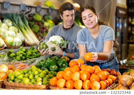 Man and woman choosing mandarin oranges and vegetables to buy in fruit and vegetables shop Man and woman choosing mandarin oranges and vegetables to buy in fruit and vegetables shop 132323348