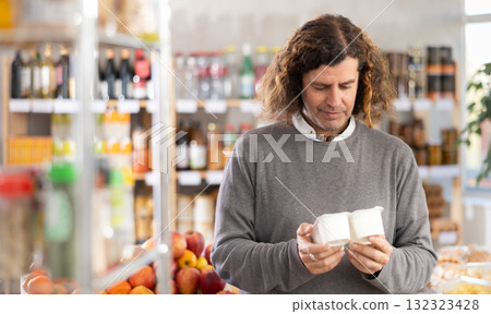 Adult man choosing yogurt in grocery store Adult man choosing yogurt in grocery store 132323428