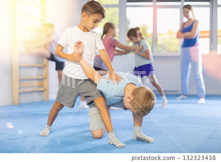 Children, boy and girl, working in pair mastering new self-defense moves at gym 132323438