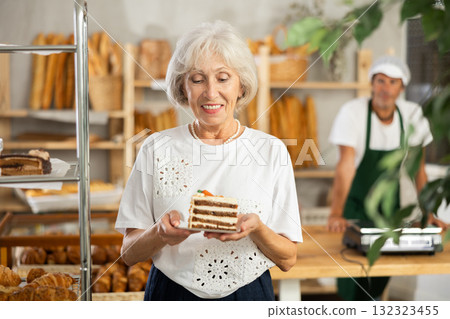 Elderly woman with piece of cake in bakery 132323455