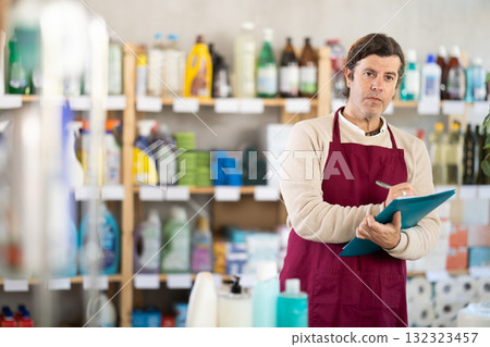 Man seller, with paper and invoice in hands, make inventory in store. Man seller, with paper and invoice in hands, make inventory in store. 132323457