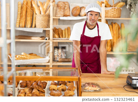 Portrait of friendly baker selling fresh baguettes and croissants in bakery 132323461