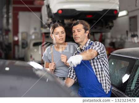 Male car repair shop worker consulting female client 132323470