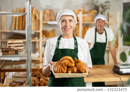 Elderly woman seller with croissants in basket Elderly woman seller with croissants in basket 132323475