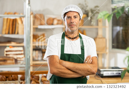 Middle-aged male seller stands in bake house, ready to greet customers Middle-aged male seller stands in bake house, ready to greet customers 132323492